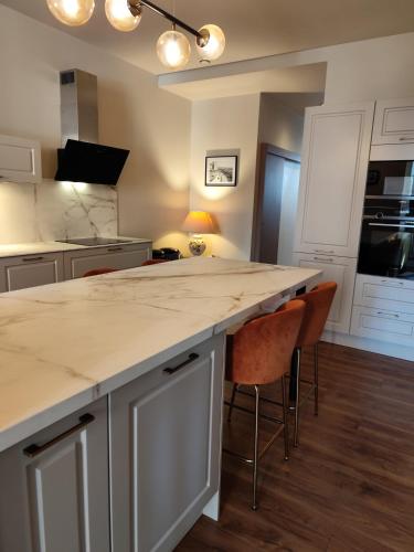 une cuisine avec un comptoir blanc et des chaises dans l'établissement Castel de Satoya, à Belfort