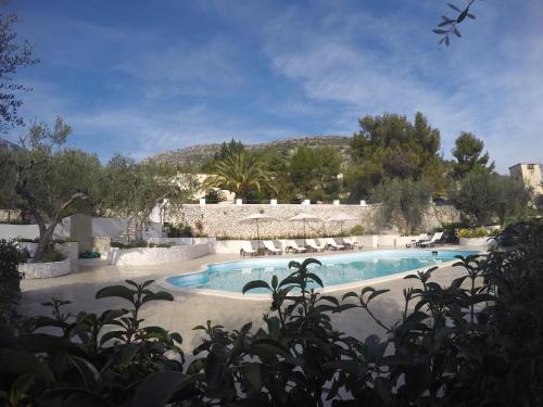 a swimming pool in a resort with a mountain in the background at Charming Puglia Villa Simone in Monte SantʼAngelo