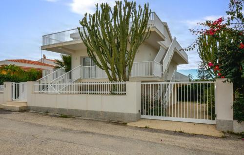 ein weißer Zaun vor einem Haus mit einem Baum in der Unterkunft Amazing Apartment In Marina Di Modica in Marina di Modica