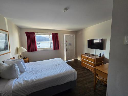 a hotel room with a bed and a desk and a television at Travelodge by Wyndham Port Elgin in Port Elgin
