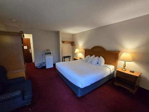 a hotel room with a large bed and a chair at Travelodge by Wyndham Port Elgin in Port Elgin