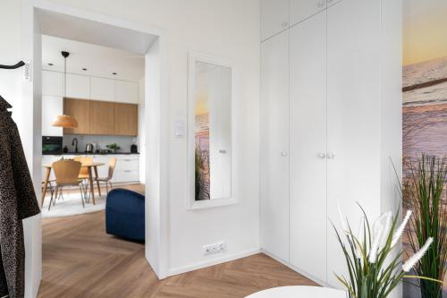 a living room with white walls and a mirror at NEMO Deluxe - 3 min od plaży i parking by Lion Apartments Sopot in Sopot