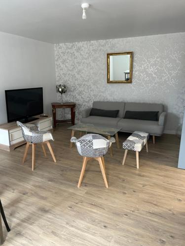 un salon avec un canapé, des chaises et une télévision dans l'établissement Gîtes à Gavray, à Gavray