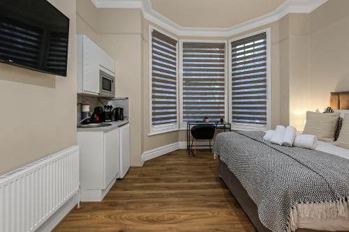 a bedroom with a bed and a desk and a kitchen at Cozy Sunlit Studio with Kitchenette in London