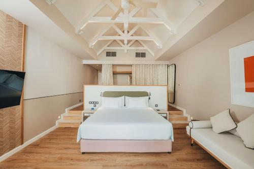 a bedroom with a white bed and a couch at Radisson Blu Azuri Resort & Spa in Roches Noires