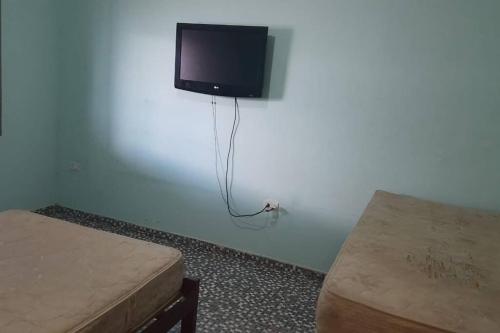 a room with two beds and a tv on the wall at Casa com Piscina no Bairro do Cercado in Araçoiaba da Serra