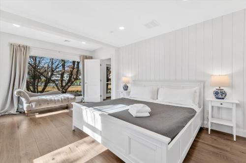 a white bedroom with a large bed and a window at Cape Cod 4 Bed Waterfront Retreat, Dock, Sleeps 8, Fire Pit, Outdoor Dining, Spa-Style Primary, Premium Kitchen with Dual Dishwashers, Gas Fireplace, River Views, Bright Open Layout, Central AC, Perfect Coastal Escape, 24 Hr Hospitality Summary in Falmouth