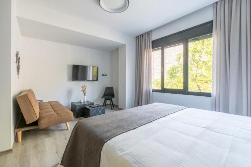 a bedroom with a bed and a chair and a window at EN Suites Stylish & Comfort Stay near Acropolis in Athens