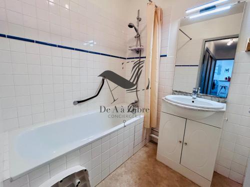 une salle de bain avec une baignoire et un lavabo dans l'établissement L'Albatros - Situé en plein coeur de ville, à Rochefort