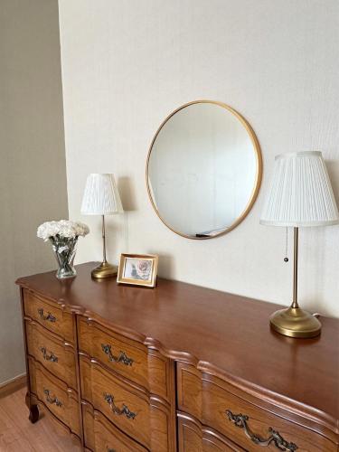 a dresser with two lamps and a mirror on it at My Happy Place in Nonthaburi