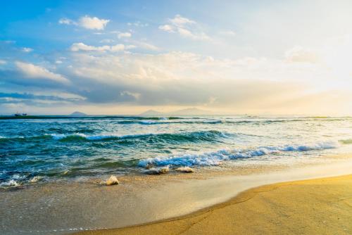a sandy beach with waves in the ocean at EasyLife Villa Hoi An in Tân Thành (1)
