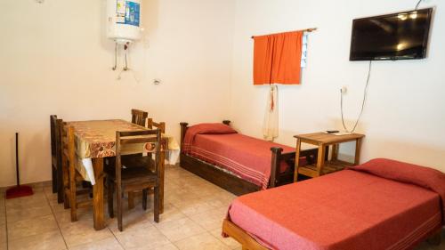 a room with two beds and a table and a desk at Monoambiente amplio con pileta in Cosquín