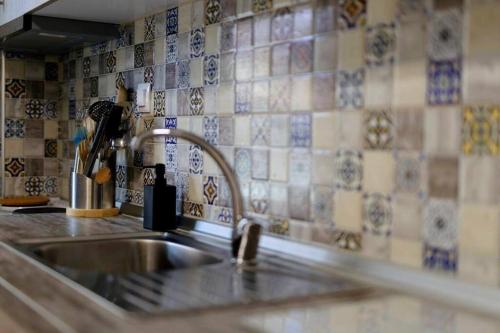 a kitchen sink with a faucet and tiles on the wall at Stefias Apartment in Kallithéa