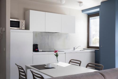a white kitchen with a table and chairs and a microwave at CHARMING MOMENT di Villa Porta - Residenza Ortensia in Luino