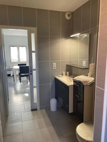 une salle de bain avec deux lavabos et une pièce avec une table dans l'établissement Appartement T2 lumineux, très bien équipé, proche centre-ville, à Salies-de-Béarn