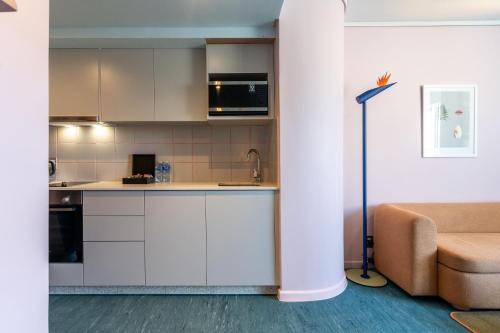 a kitchen with white cabinets and a couch in a room at The Tropicana Hotel in Cape Town
