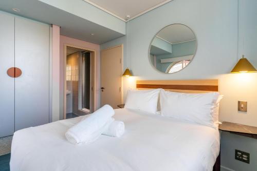 a bedroom with a white bed and a mirror at The Tropicana Hotel in Cape Town