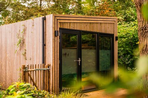 a small wooden shed with a glass door at Boshuisje Zelhem in Zelhem
