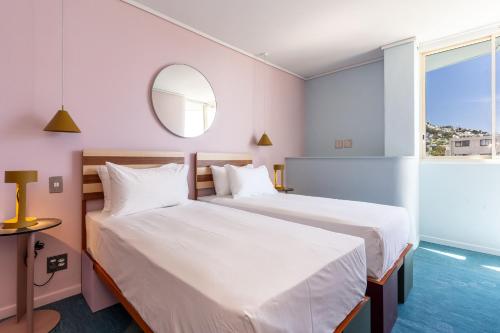 two beds in a hotel room with a mirror at The Tropicana Hotel in Cape Town