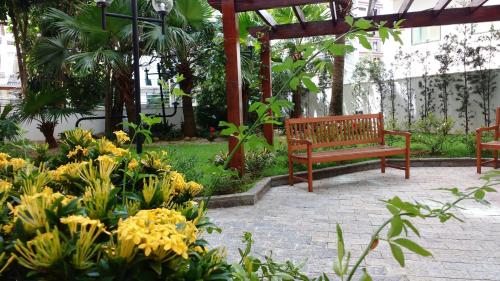 a wooden bench in a garden with yellow flowers at Mercure Sao Paulo Alamedas in Sao Paulo
