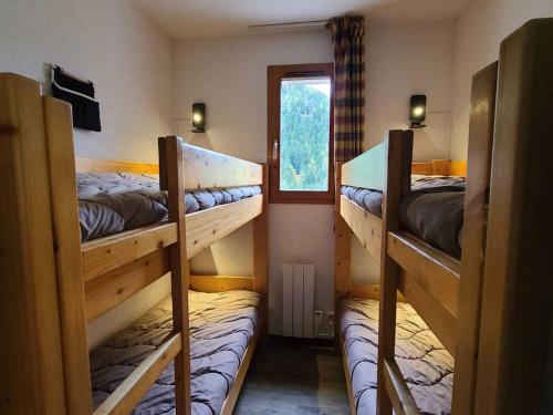 une chambre avec trois lits superposés et une fenêtre dans l'établissement Appartement 3 Pièces + Cabine 8/10 Pers. - Cœur de Station, Proche Pistes et Commerces, 55m² - FR-1-265-191, à Valfréjus