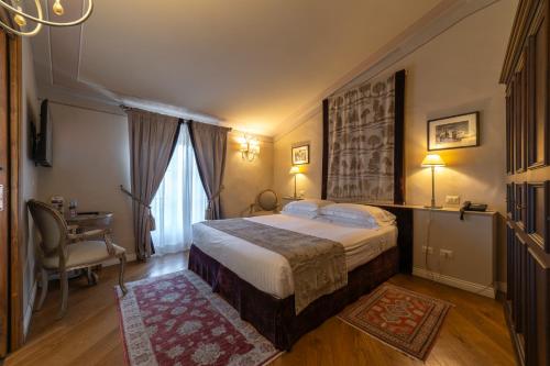a hotel room with a bed and a desk and a chair at Palazzo Leopoldo Dimora Storica & Spa in Radda in Chianti