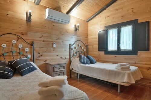 Dos camas en una habitación con paredes de madera. en Villa Ronda, en La Cimada