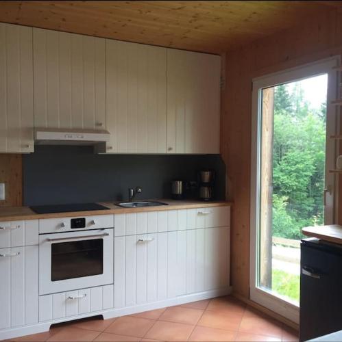 a kitchen with white cabinets and a large window at Chalet im Wanderparadies in Annaberg im Lammertal