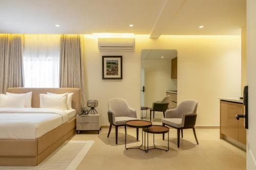 a hotel room with a bed and a table and chairs at Clay House by Husk Collection in Abuja