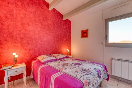 une chambre avec un lit et un mur rouge dans l'établissement Appartement - La Conque, au Cap d'Agde