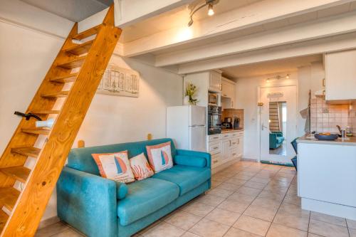 un salon avec un canapé bleu et une cuisine dans l'établissement Appartement - La Conque, au Cap d'Agde