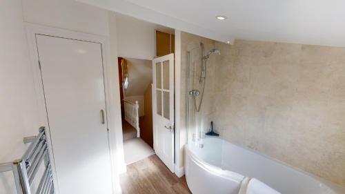ein weißes Bad mit einer Badewanne und einer Treppe in der Unterkunft Holmdean Cottage in Sidmouth