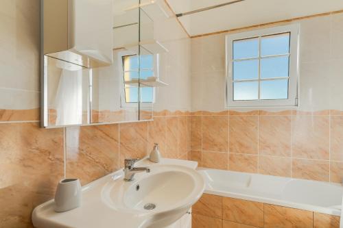 a bathroom with a sink and a mirror and a tub at Villa Nobrega by Holiday Rental Madeira in Funchal