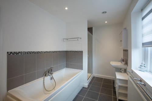 une salle de bains avec baignoire et lavabo dans l'établissement Bakery Cottage, à East Budleigh