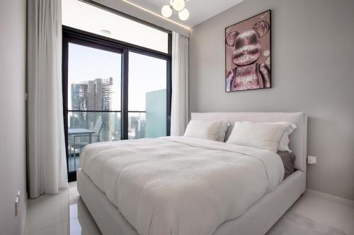 a white bedroom with a large bed and a large window at Burj KHALIFA VIEW SMART HOME ZADA TOWER in Dubai