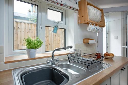 eine Küche mit Spüle und Fenster in der Unterkunft Salty Cottage in Sidmouth