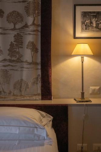 a lamp sitting on a table next to a bed at Palazzo Leopoldo Dimora Storica & Spa in Radda in Chianti