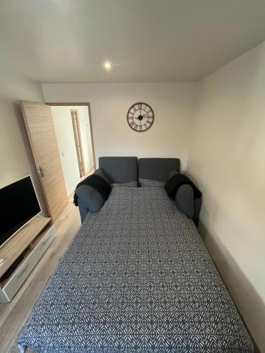 a bed in a room with a clock on the wall at Appart 4 personnes proche PARIS Tour Eiffel in Meudon