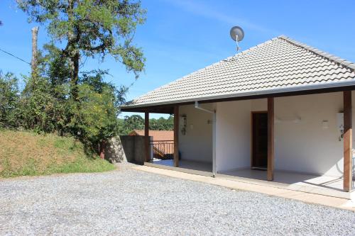 a small white house with a roof at Apart Avenida Monte Verde in Monte Verde
