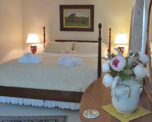 a bedroom with a bed and a vase with flowers on a table at Virginia Country Cottage, GREAT Location, Pets in Troutville