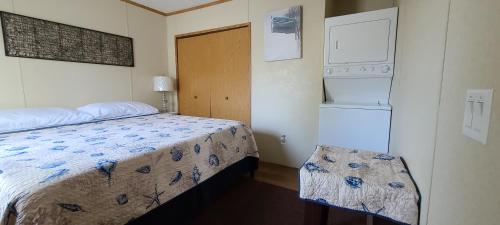 a small bedroom with a bed and a refrigerator at The Beach House in Hillsboro