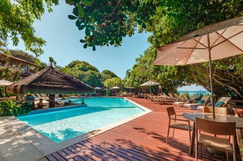 a pool at a resort with tables and chairs at Hotel Ponta do Madeiro in Pipa