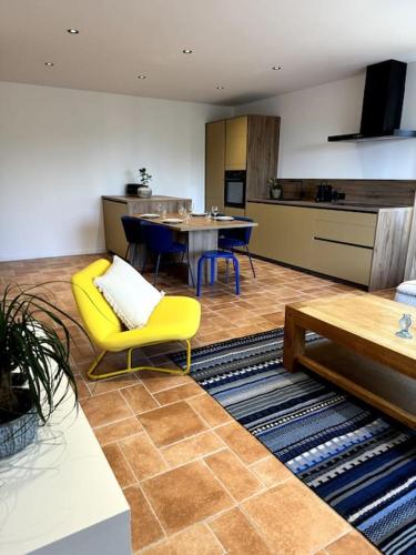 a living room with a yellow chair and a kitchen at Appartement Centre Ville in Porto-Vecchio