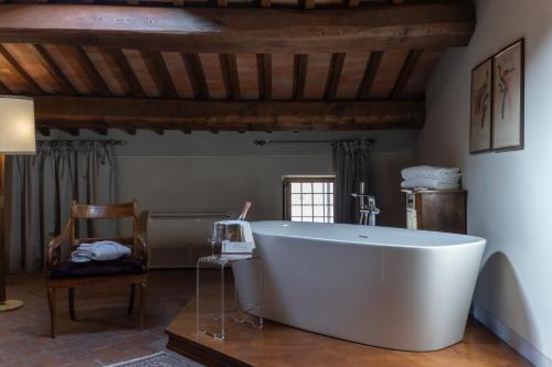 a large white bath tub in a room with a chair at Palazzo Leopoldo Dimora Storica & Spa in Radda in Chianti