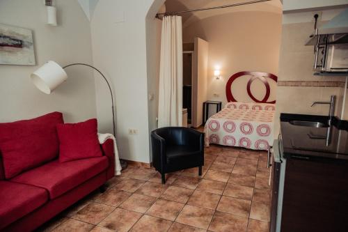 a living room with a red couch and a bed at Apartamento Las Avutardas 1 in Cáceres