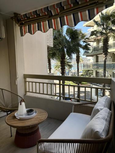 - un balcon avec un canapé, une table et des palmiers dans l'établissement Résidence Neptunia, à Juan-les-Pins