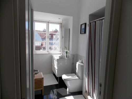 a bathroom with a toilet and a sink and a window at Joia da Mouraria in Lisbon