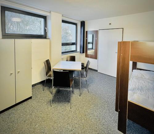 a room with a table and chairs and a bed at Jugendherberge City-Hostel Köln-Riehl in Cologne