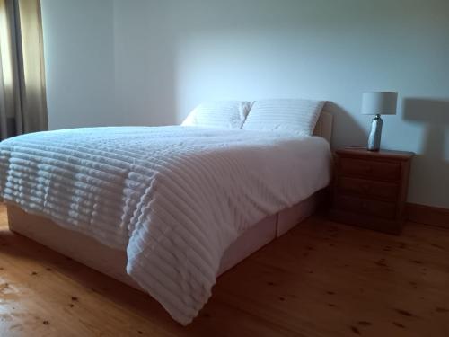 a bed with white sheets and a lamp on a wooden floor at Global Guest Ireland in Williamstown