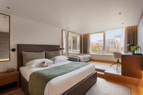 a bedroom with a large bed and a desk and windows at Royal Garden Hotel in London